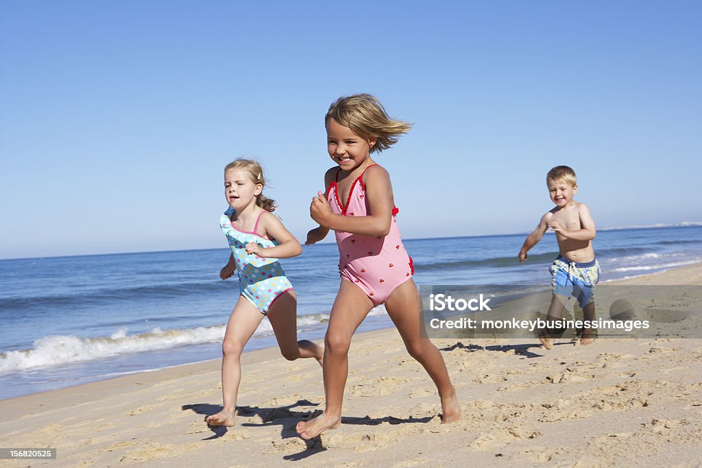 Tres niños corriendo en la playa - Foto de stock de Carrera libre de derechos