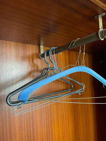 Stock photo showing an empty hotel closet with  plastic and wire  coat hangers on a metal rail.