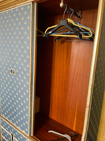 Stock photo showing an empty hotel closet with  plastic and wire coat hangers on a metal rail.