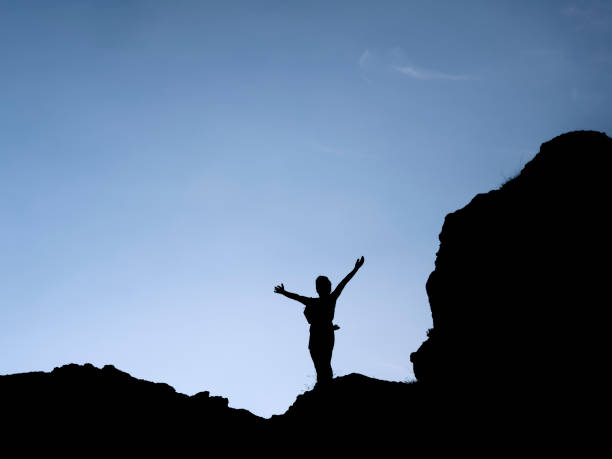 istock Silhouette of woman with open arms 1568235586