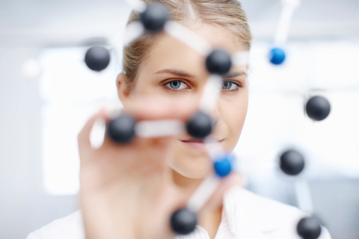 Portrait of a gorgeous female scientist looking through a molecular structure model