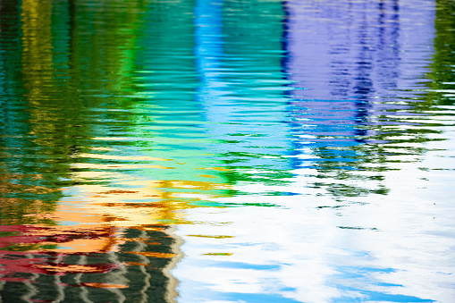 This is an abstract photograph of the rainbow colored amphitheater reflecting on the water’s surface at Lake Eola in downtown Orlando, Florida.