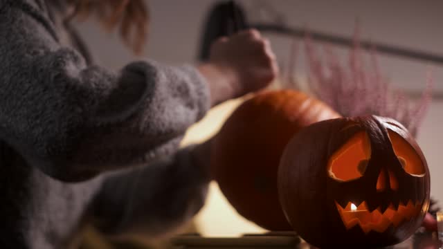 Halloween at Home: woman is carving a pumpkin face