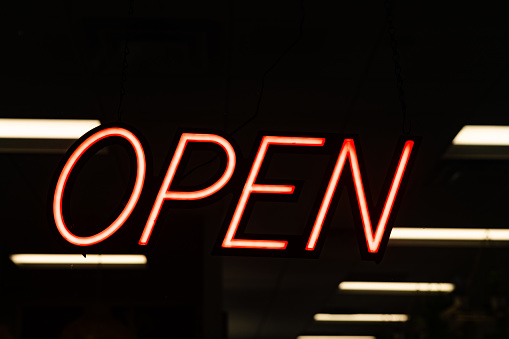 This is a photograph of a neon open sign with a dark background in downtown Orlando.