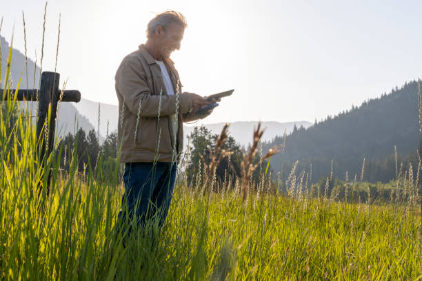 istock Rancher uses digital tablet while resting by wooden fence 1568304453