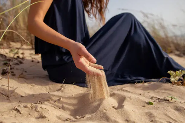 Sand running through woman hands at the beach. Time running concept. Sensory Experiences at your fingertips