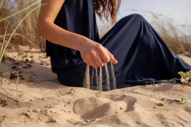 Sand running through woman hands at the beach. Time running concept. Sensory Experiences at your fingertips