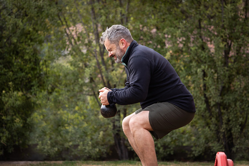 Overweight adult man exercising with dumbbells outdoors - Buenos Aires - Argentina