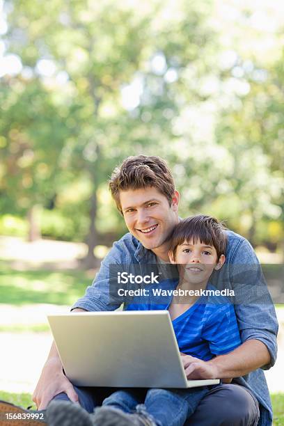 Foto de Sorridente Menino E Seu Pai Sentados Tanto Usando Laptop e mais fotos de stock de 30 Anos