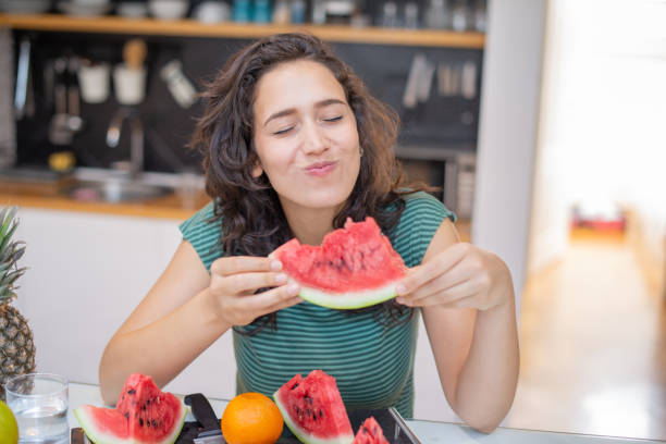istock Beautiful young woman having breakfast in the kitchen 1568434890