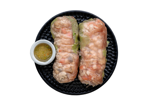 Homemade spring rolls wrapped in riceberry rice paper stuffed with sliced chicken and fresh vegetables served with asian chili sauce isolated on white background with clipping path. Top view, Selective focus.