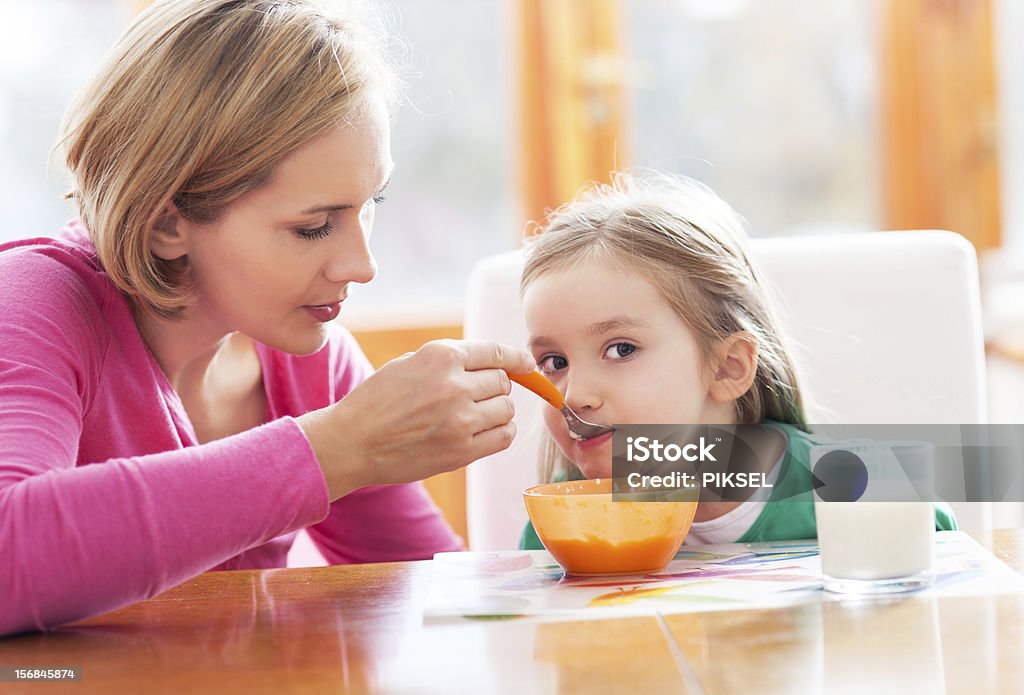 Mother feeding her daughter by spoon Adult Stock Photo