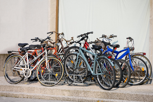 A group of old partly rotten colorful abandoned rusted simple cycles partly locked partly damaged in front of monotonous background as a concept for mobility with single lane vehicles bike paths and bicycles