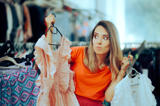 istock Undecided Woman Choosing Between Two Blouses in a Store 1568520089