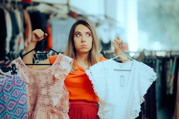 istock Undecided Woman Choosing Between Two Blouses in a Store 1568520092