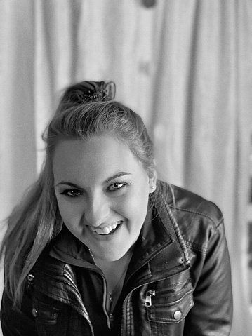 Homemade Photo Booth Portrait of a beautiful young woman. She is bent over laughing and smiling. Photograph is in black and white.