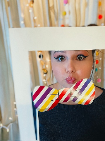 Cute teen girl making a funny face with Photo Booth props at a birthday party with a homemade Photo Booth.