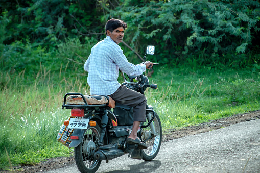 Pune, India - July 23 2023: Indian man on a motorcycle stares at the camera at Uruli near Pune India.