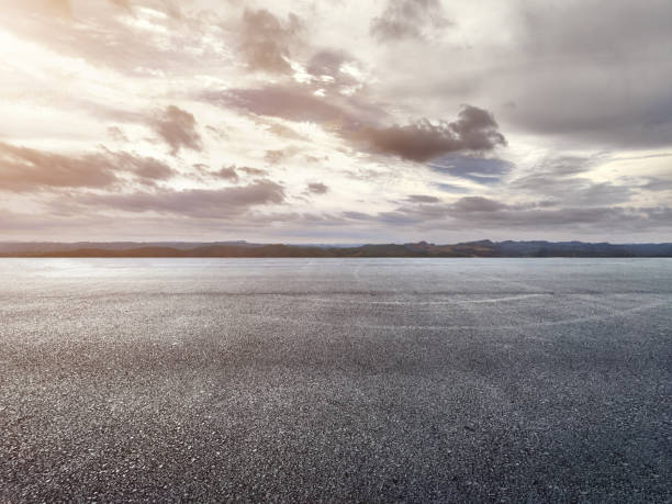 istock Asphalt road and sky with clouds at sunset, high angle view 1568635549