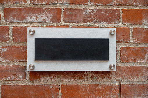 Blank metal sign on a brick wall.