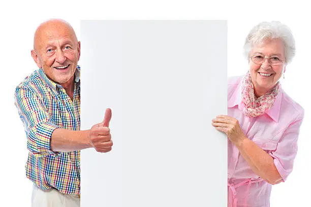 Photo of happy smiling senior couple with a blank board