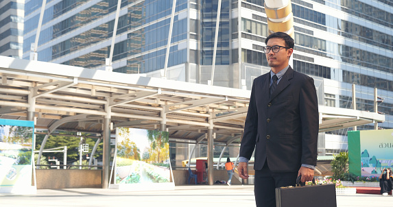 Asian businessman wear suit eyeglasses standing street modern city. Young handsome asian business man look at bright future smart confident. Entrepreneur executive lawyer man cityscape outside office