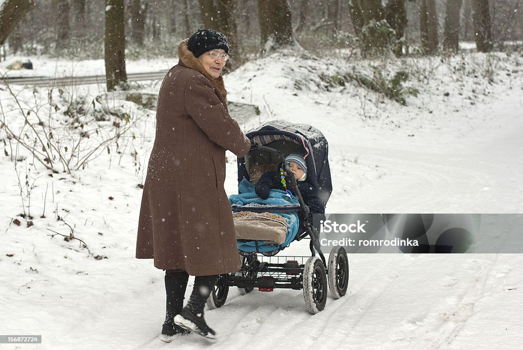 Great-nonna, camminando con bambino nel passeggino durante una nevicata - Foto stock royalty-free di 12-17 mesi