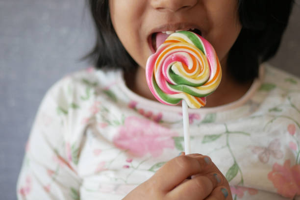 istock child is licking colorful candy on stick, 1568742069