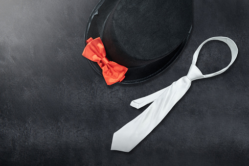 Black hat and silver tie with a red bow tie on a colored background. Fathers day concept
