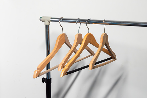 close up of clothes hangers in a row on a white background, wooden hangers on a white background,empty clothes hangers hanging on an empty holder