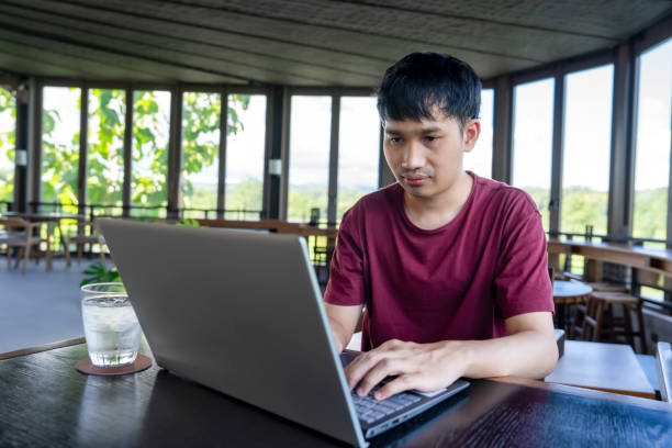 istock young asian man working remotely on internet online over laptop on vacation,take a break in cafe on the mountain, destination in Thailand. concept of travel freely,digital nomad 1568749098