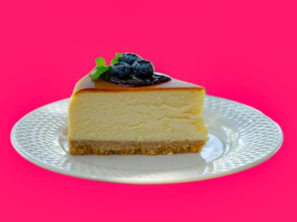 istock Isolated Cheesecake topped with blueberries on white plate on pink background. 1568755859