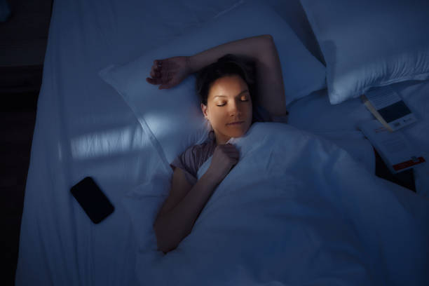 Above view of relaxed woman taking a nap in bed at night. High angle view of a woman taking a nap in her bed at night. woman sleeping in bed at night stock pictures, royalty-free photos & images