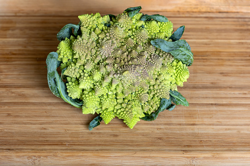 Romanesco broccoli on wooden board on kitchen table