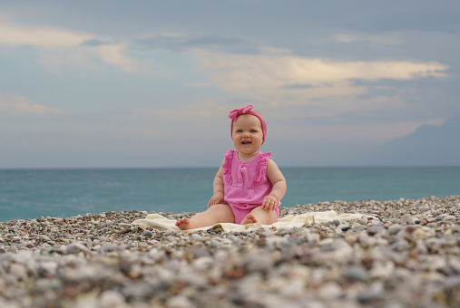 Cute little baby girl sitting on the sand, Konyaalti Beach, Antalya