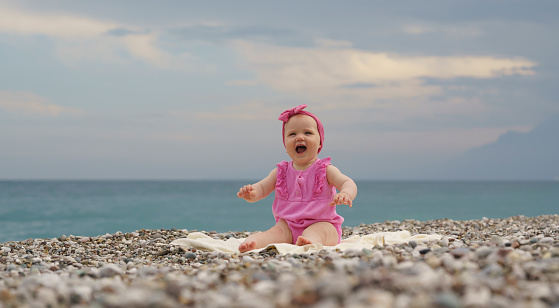 Cute little baby girl sitting on the sand, Konyaalti Beach, Antalya