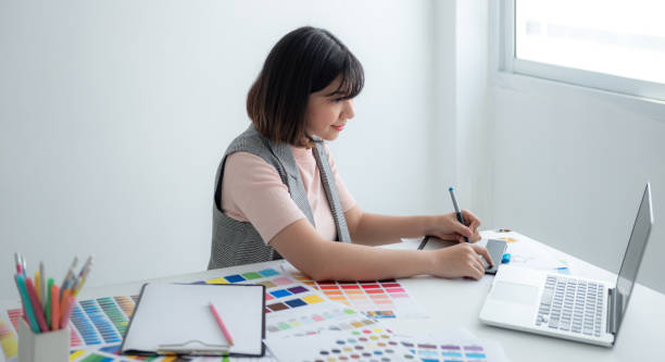 istock Designer using laptop to design fashion clothes. 1568808339