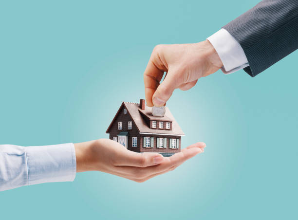 istock Man putting a coin in a model house 1568877577