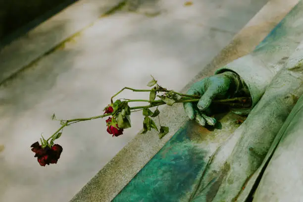 Photo of Detail of Victor Noir's bronze statue in Père Lachaise Cemetery, holding red roses