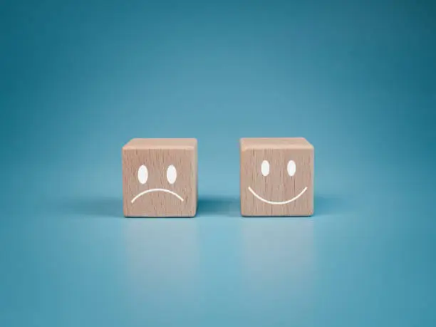 Photo of Mental health and emotional state concept, Smile face  and sad face on wooden block cube for positive mindset selection concept.