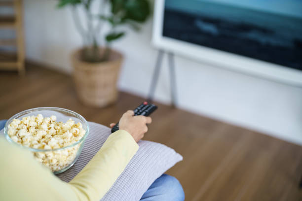 istock Asian woman Watching smart TV and using remote controller Hand holding television audio remote control at home with the remote control television 1568910695