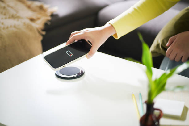 istock Charging mobile phone battery with wireless charging device in the table. Smartphone charging on a charging pad. Mobile phone near wireless charger Modern lifestyle technology concept. 1568910733