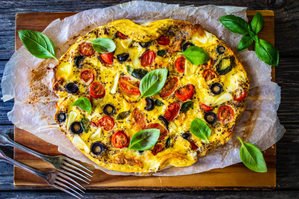 istock Frittata - scrambled eggs with mozzarella and vegetables on wooden table 1568913379