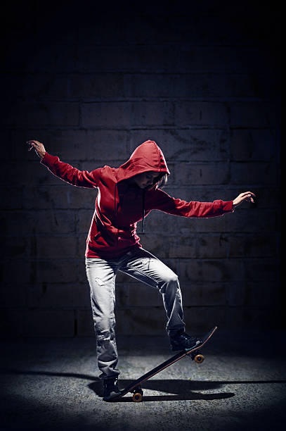 istock Spotlighted male skateboarder in red hoodie doing tricks 156891649