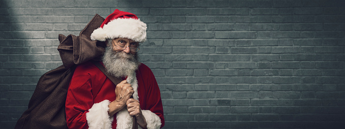 Smiling Santa Claus carrying a sack with gifts on Christmas Eve