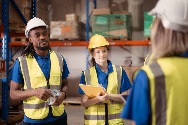 istock Side view of warehouse workers discussing inspecting goods brought into the warehouse for pre-stocking. 1568918283