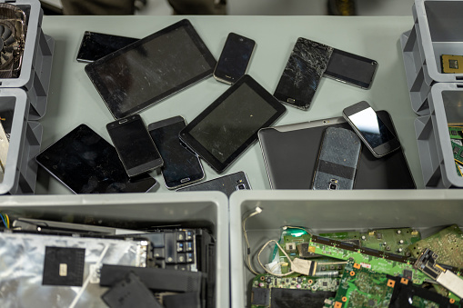 Overhead view of old smart phones and digital tablets on desk in recycling centre.