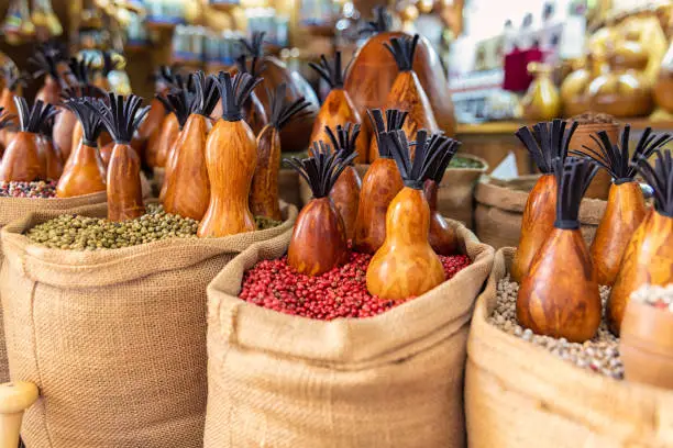Bags full of various multicolored spices and traditional wooden saltshaker as souvenir on a market stall. Close up. selected focus. Bukhara, Uzbekistan, Central Asia