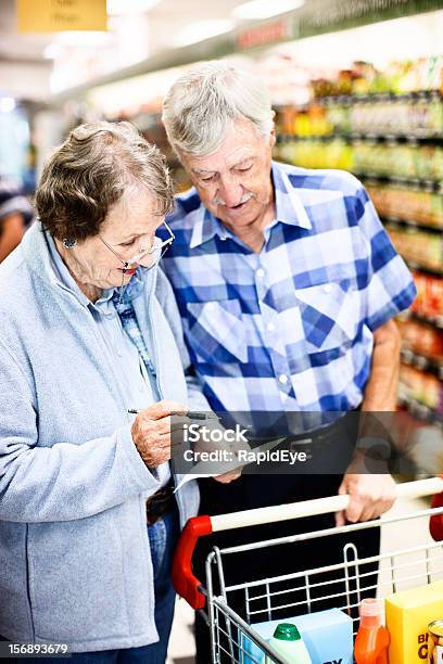 Senior Shoppers Check Grocery List In Supermarket Stock Photo - Download Image Now - 80-89 Years, Active Seniors, Adult