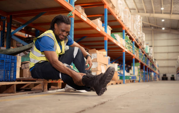 istock Warehouse worker with pain after a leg accident while working in a large warehouse 1568938476